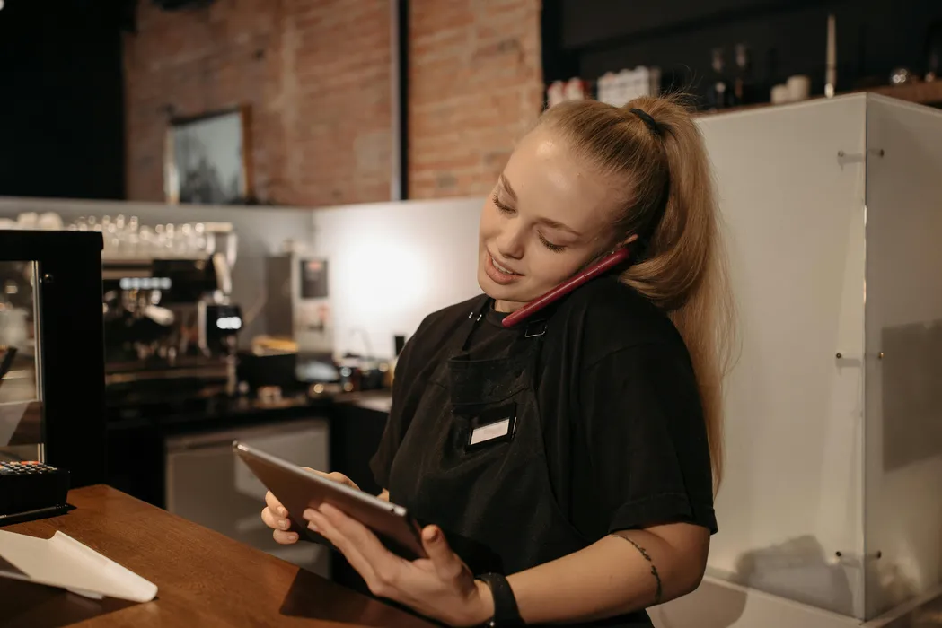 Café operator managing direct orders and customer communication on phone and tablet